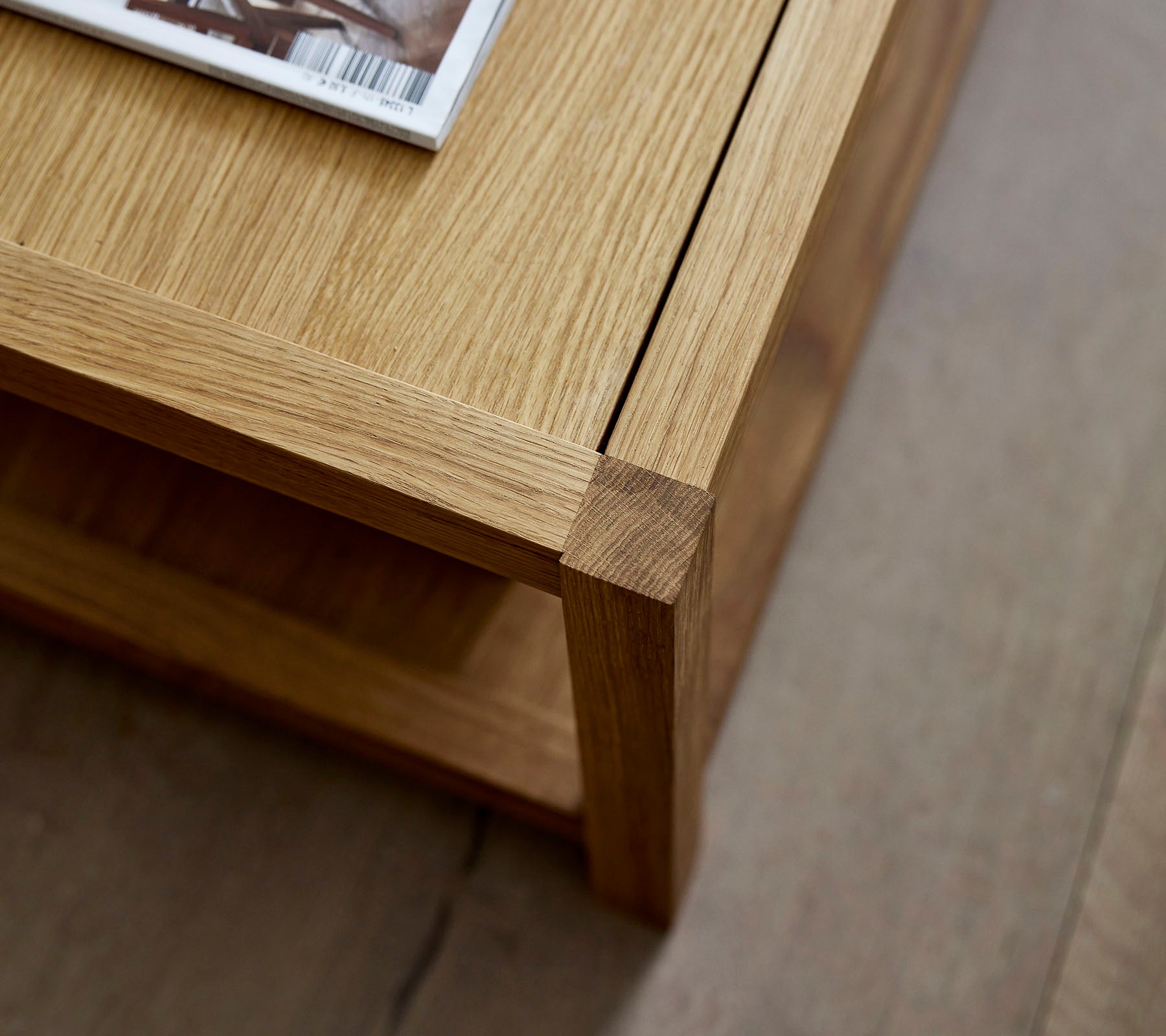 Wooden coffee table with a clean design, featuring a magazine placed on top and a minimalist lower shelf for additional storage.