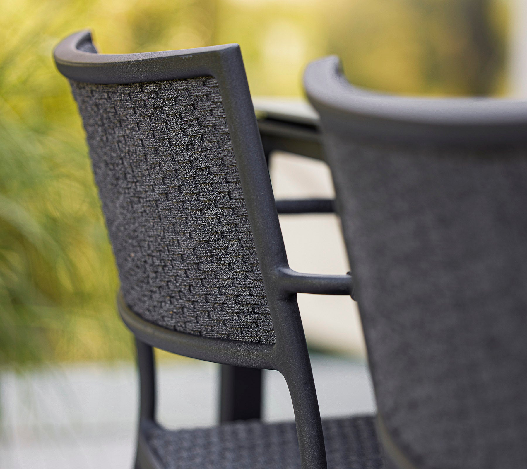 Close-up of a stylish chair with a woven backrest, showcasing a modern design in shades of gray. Perfect for contemporary spaces.