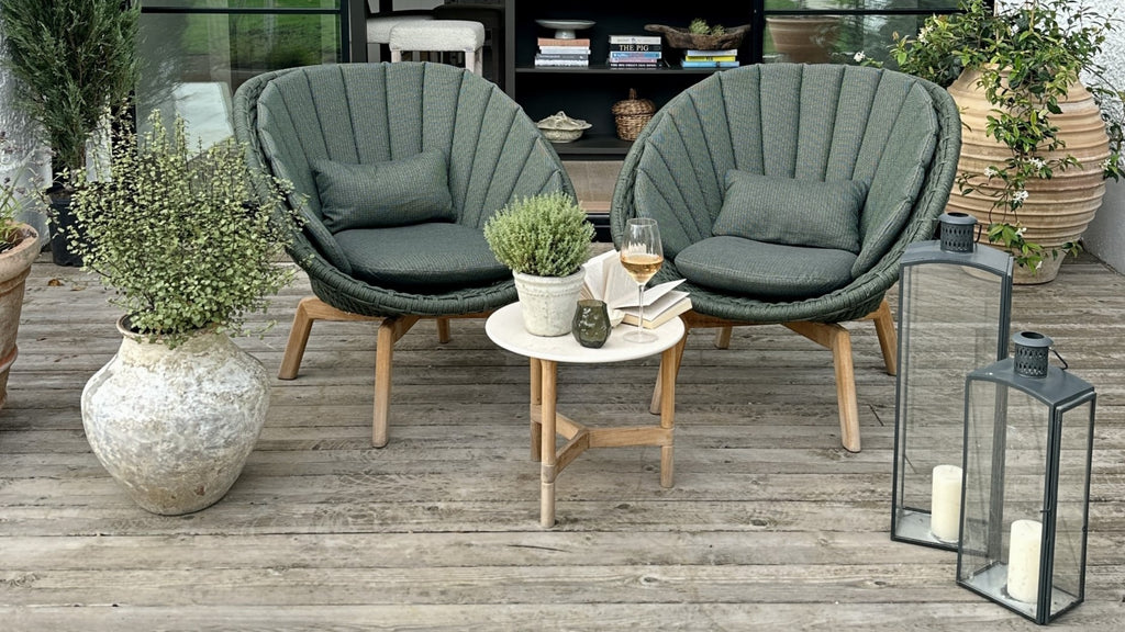 Two outdoor lounge chairs in dark green with a white small round side table
