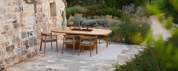 Rustic wooden table with matching chairs in a garden setting.