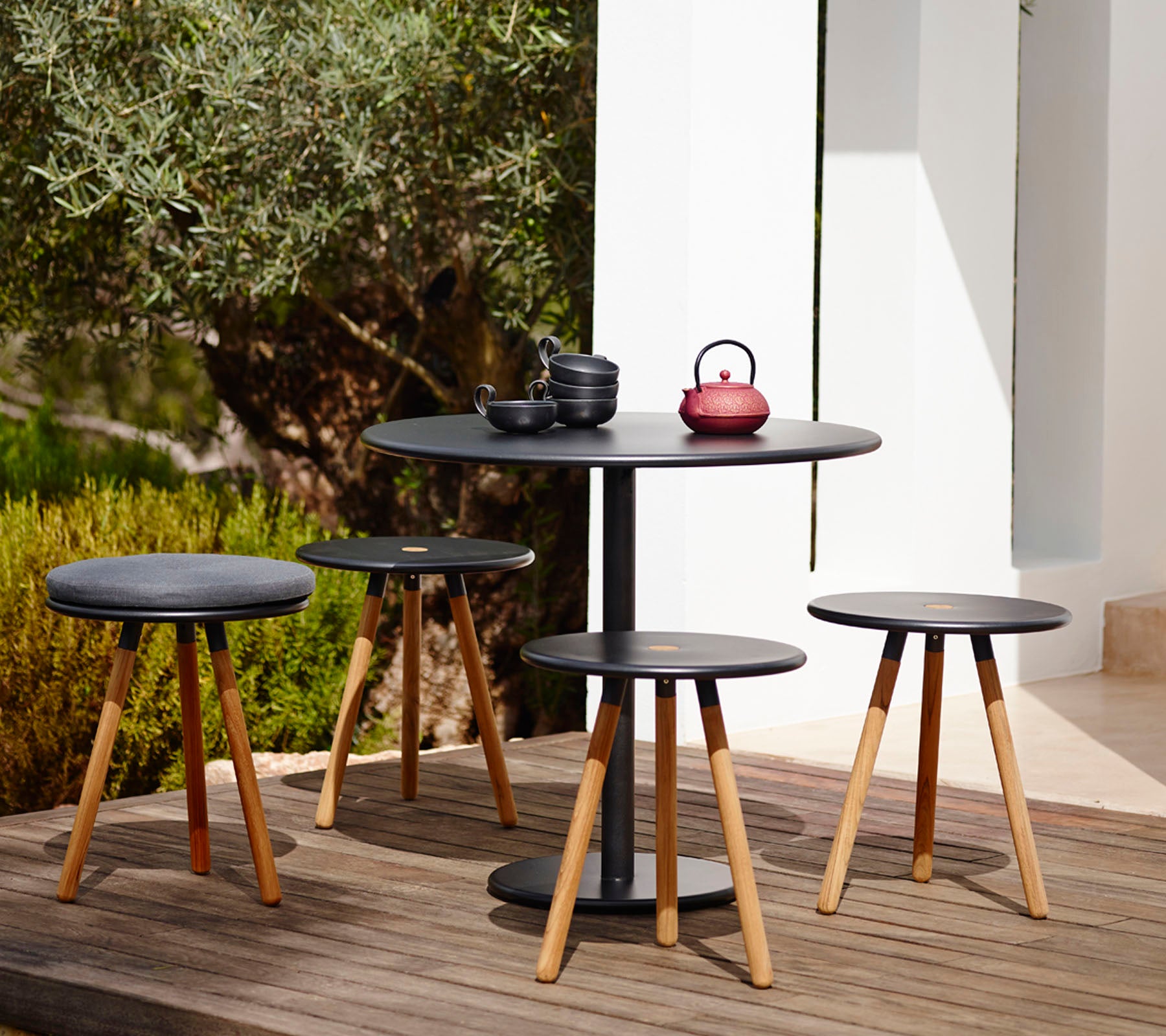 Modern black table and stools set in an outdoor garden setting.