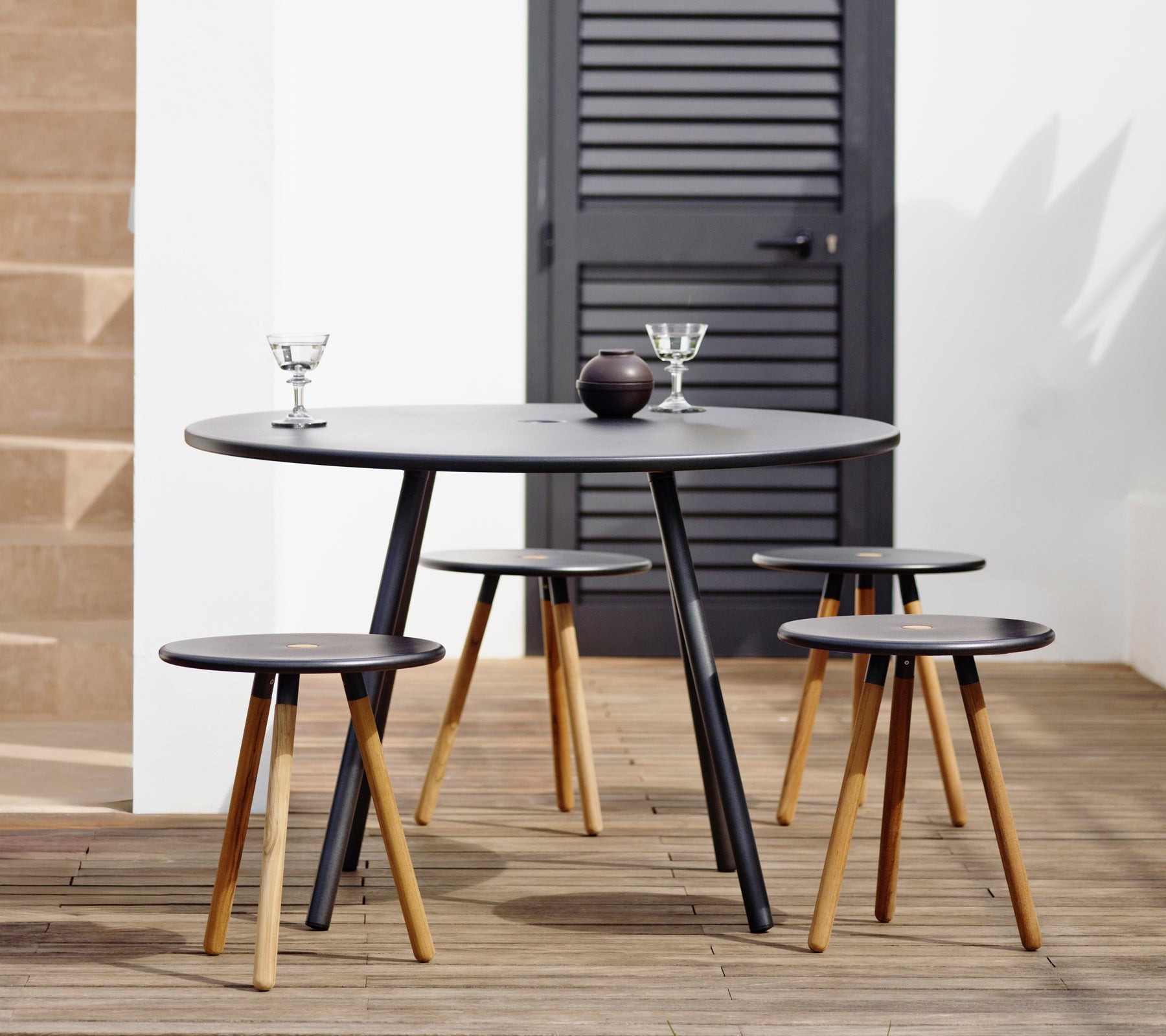 Modern black table with matching stools in a stylish lounge setting.