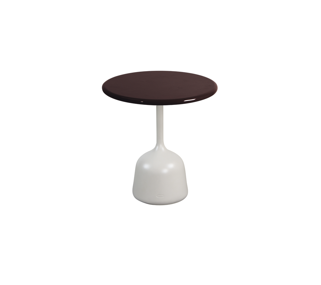Burgundy round table with a white base in a modern lounge setting.