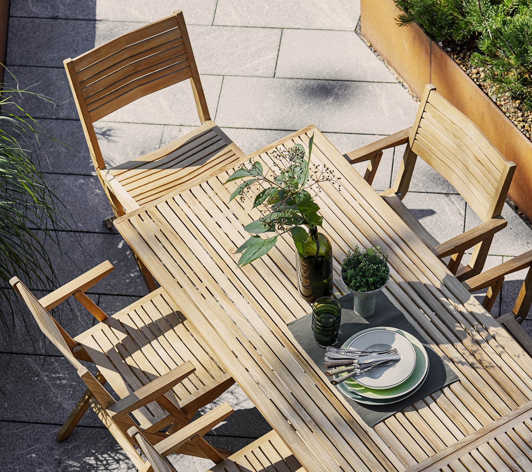 Wooden dining set featuring a rectangular table and folding chairs, adorned with greenery and tableware for an inviting setting.