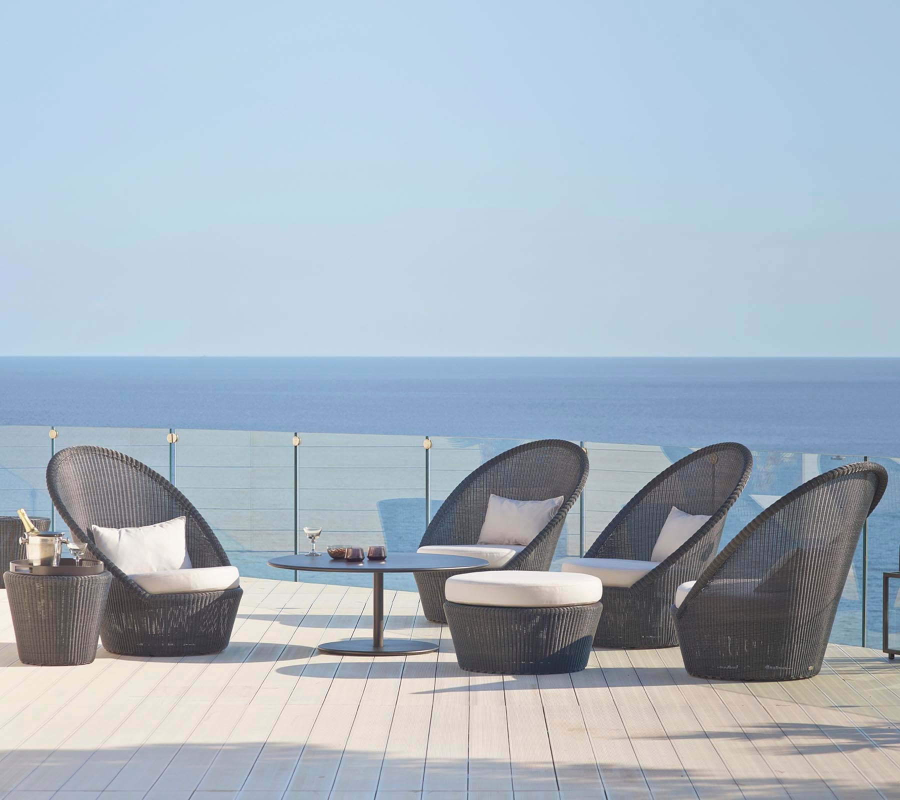 Stylish seating set featuring curved chairs and a matching table, set against a serene ocean backdrop. Ideal for relaxation.