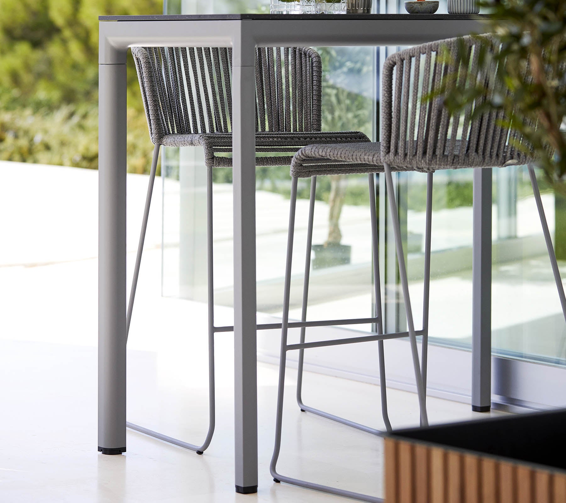 A sleek, modern table with matching high chairs featuring a minimalist design and stylish metal frame, complemented by natural greenery.
