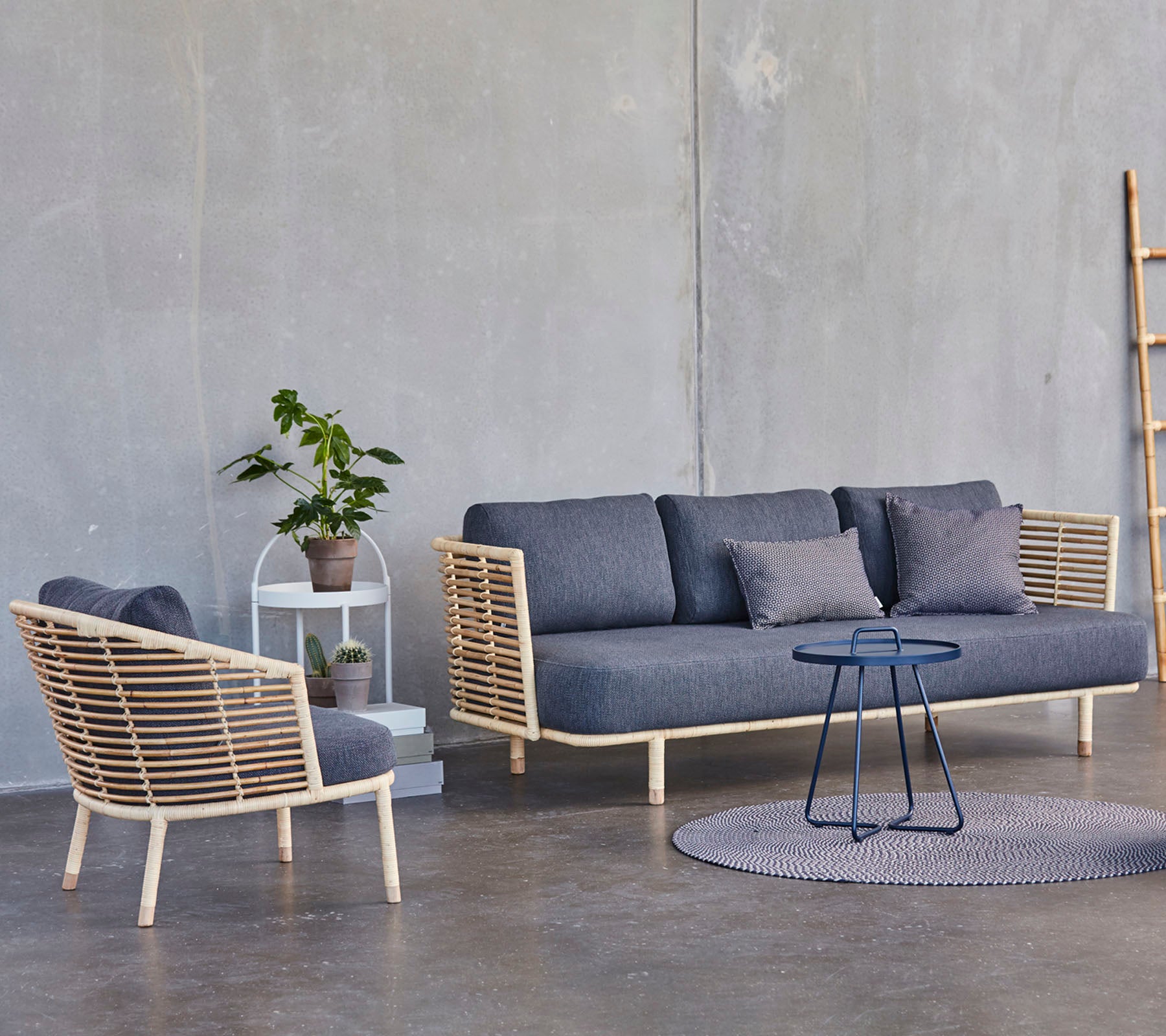 A modern seating arrangement featuring a stylish sofa and armchair with wooden accents, accompanied by a small side table and a potted plant.