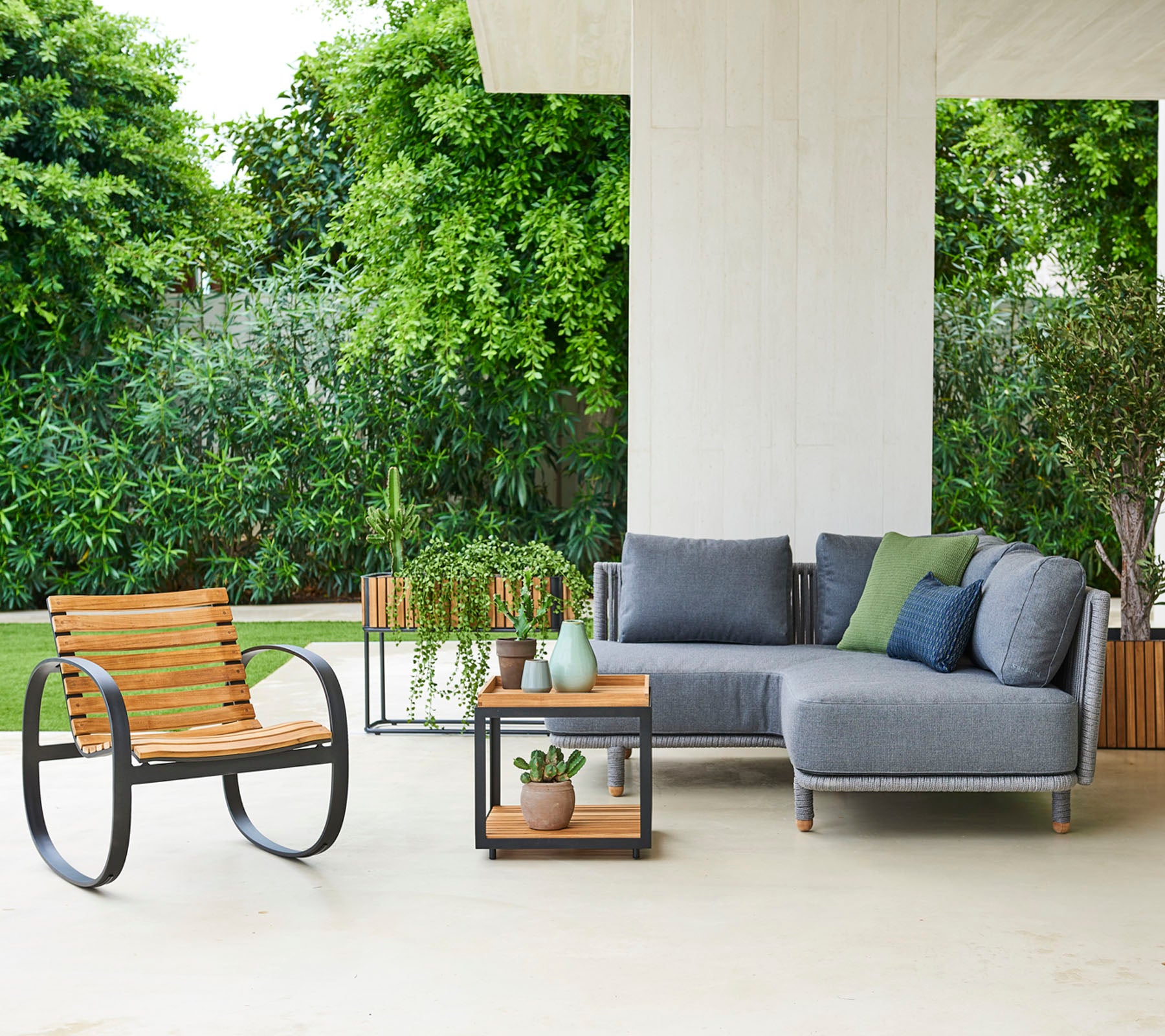 Contemporary seating arrangement featuring a modular sofa with cushions, a stylish chair, and a side table with decorative plants.