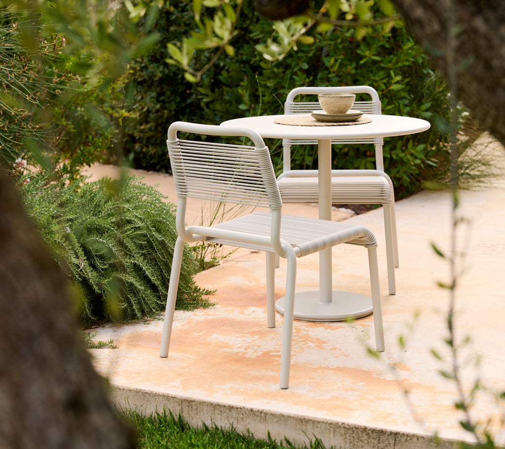 Modern sand-colored chair and table set in a natural outdoor setting.