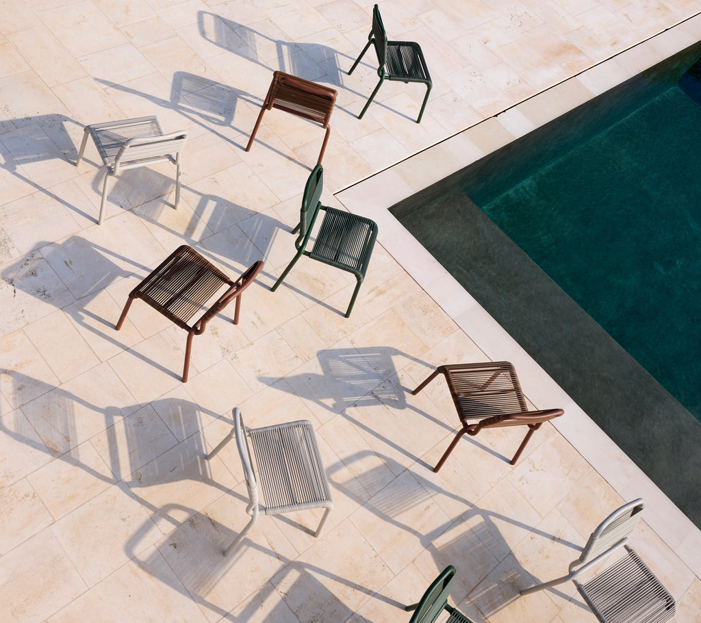 Collection of modern chairs in various colors around a swimming pool.
