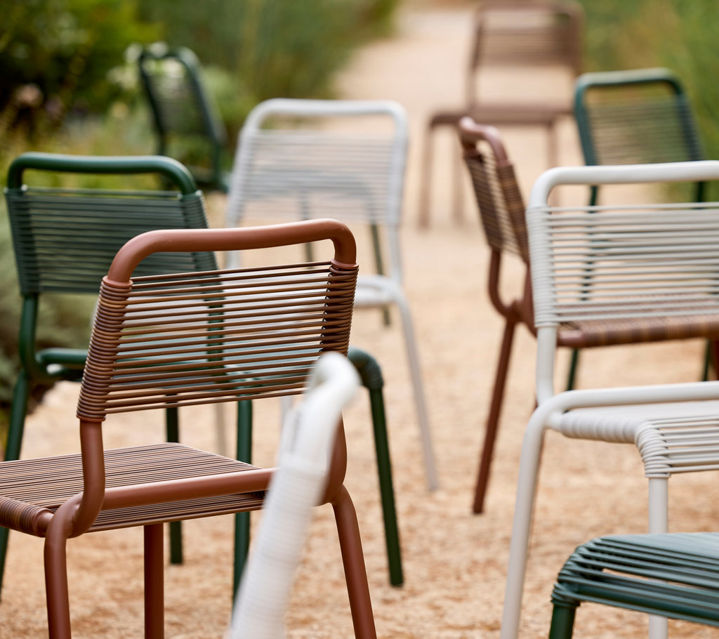 A collection of modern chairs in green, brown, and white along a pathway.