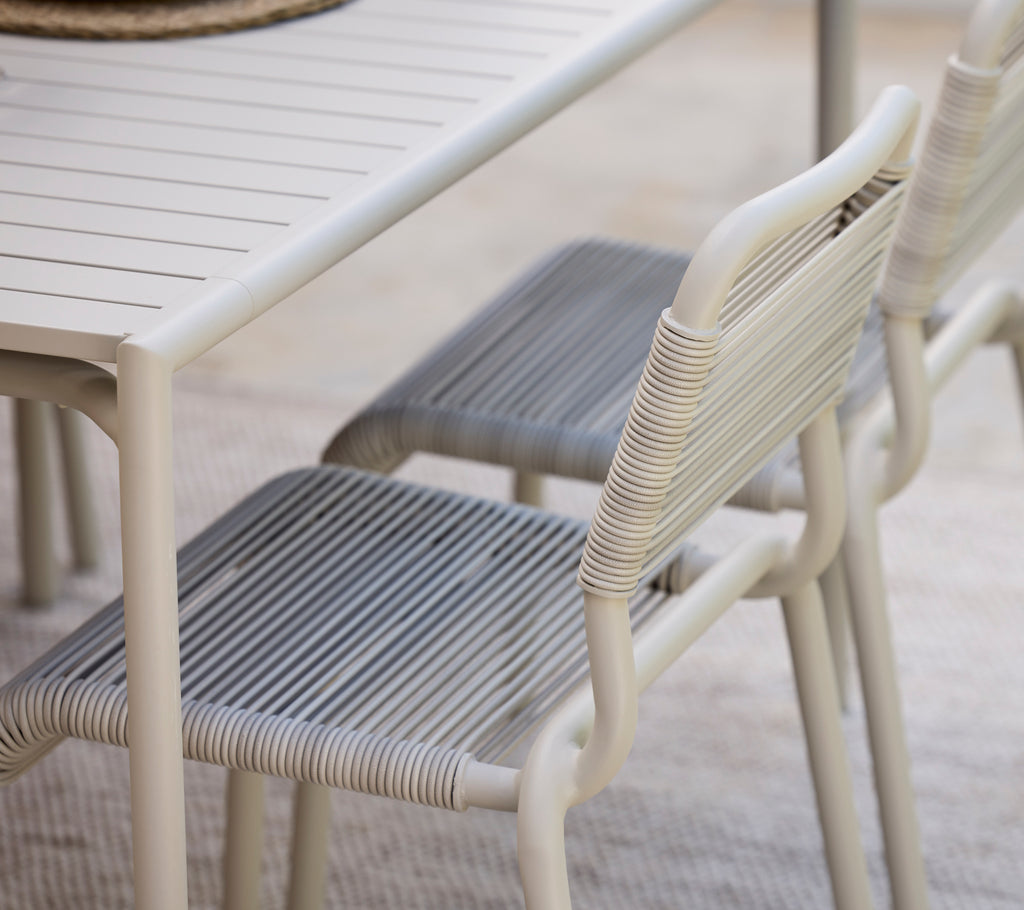 Modern dining table with white finish and grey chairs.