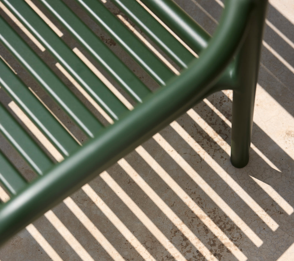 Green chair casting shadows on a surface.