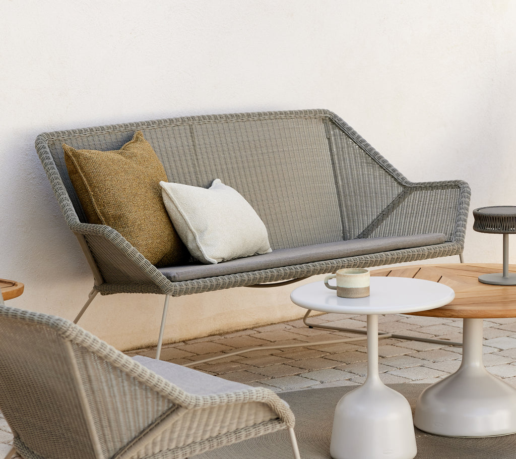 Modern lounge area featuring a grey sofa with cushions and round tables.