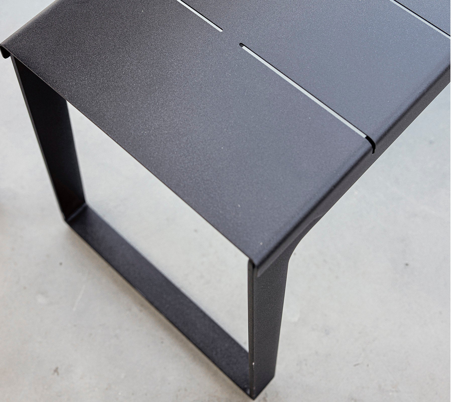 Black metal table with a sleek design and minimalist aesthetic, featuring a slatted top and sturdy frame. Ideal for modern settings.