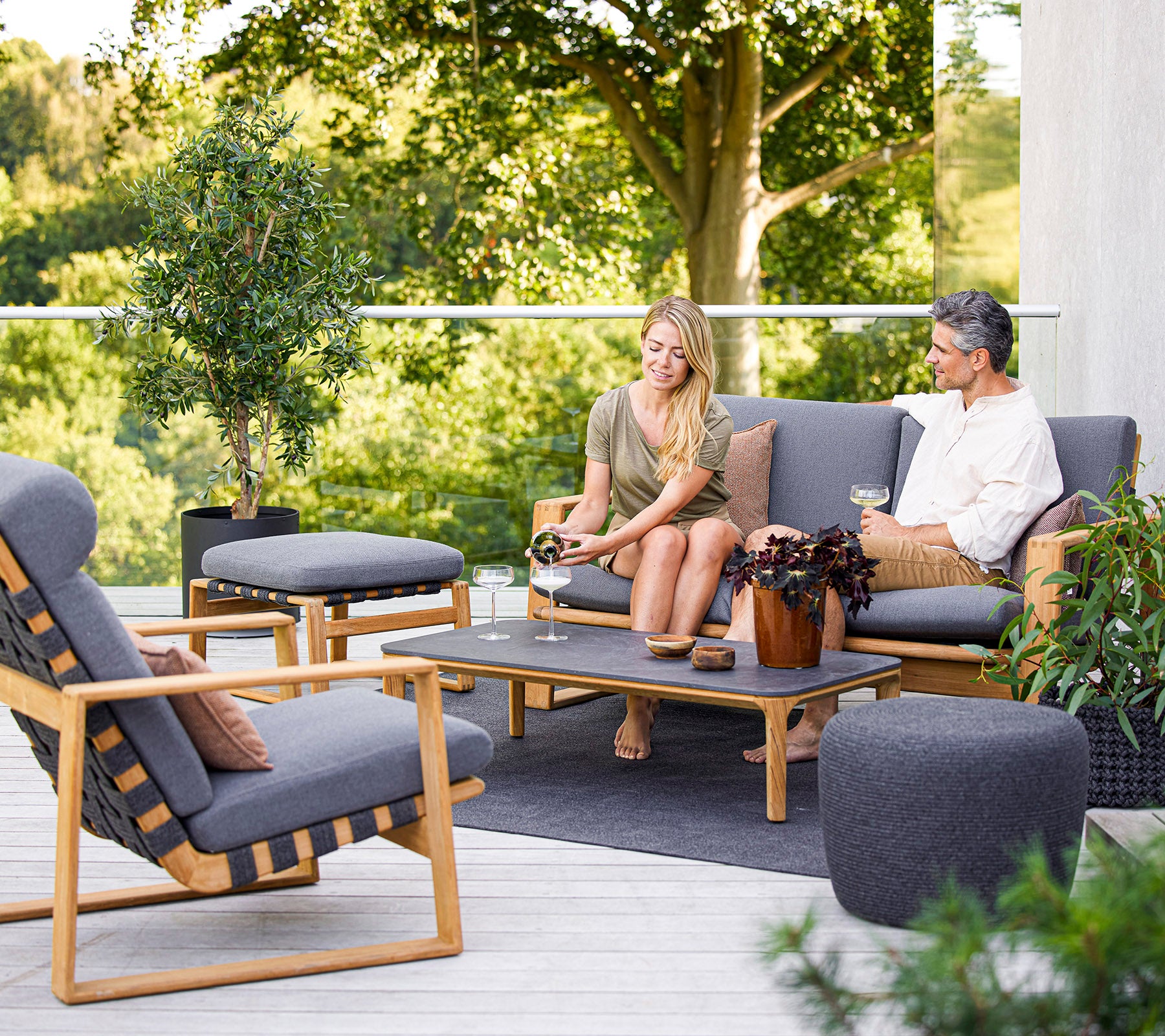 Two people enjoying a conversation on a stylish outdoor seating arrangement surrounded by greenery.