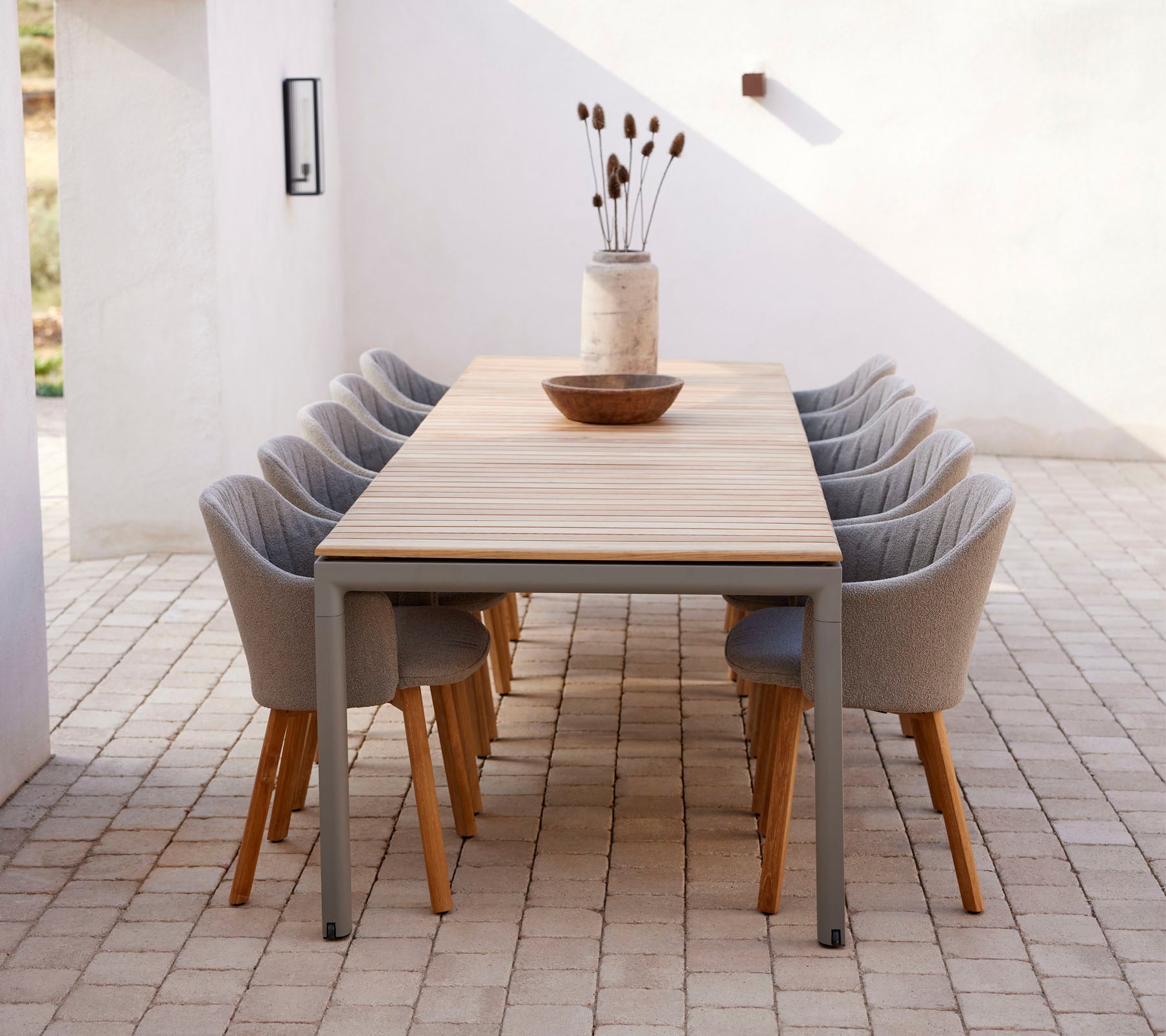A long table with modern chairs, styled with a decorative vase and bowl, creating a welcoming space for gatherings.