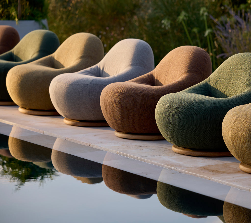 Set of modern lounge chairs in shades of grey, brown, and green by a pool.