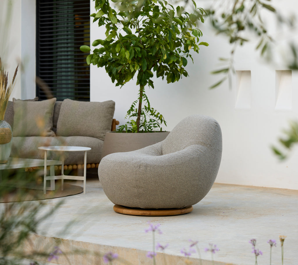 Modern lounge setting featuring a grey chair, grey cushion, and white table.