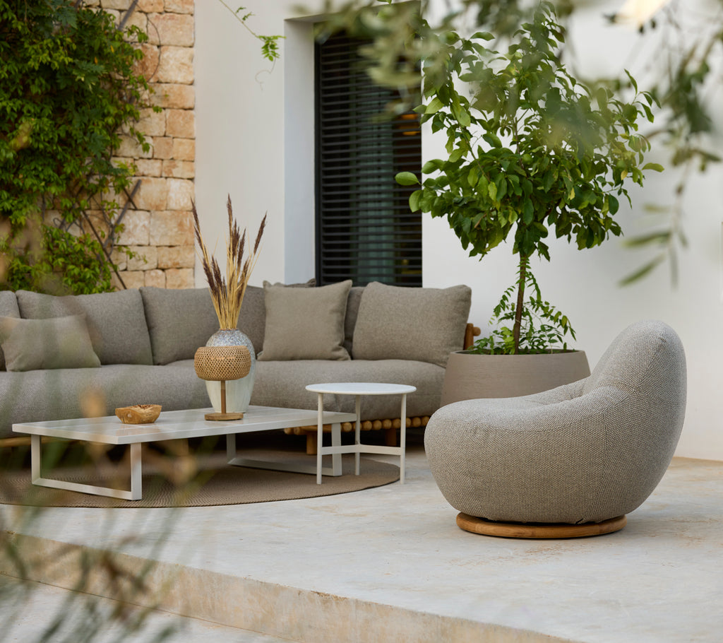 Modern lounge area with a grey sectional sofa, white coffee table, and round chair.