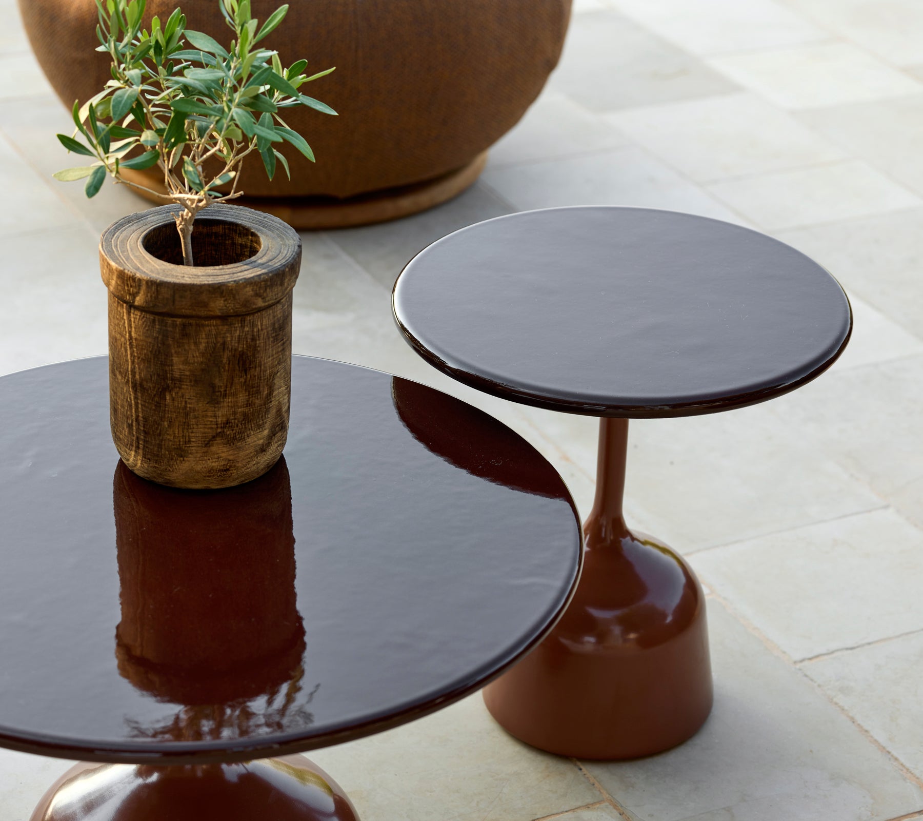 Two modern brown tables with a potted plant in a stylish lounge setting.