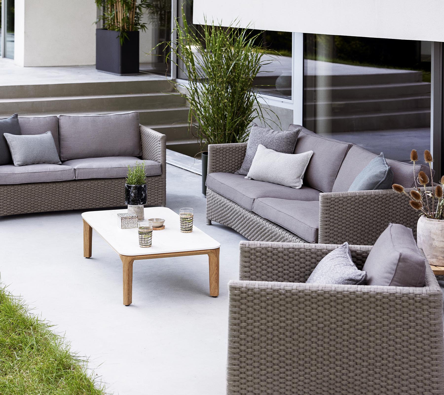 Contemporary outdoor seating arrangement featuring a 2-seater sofa, 3-seater sofa, lounge chairs, and a coffee table with decorative items.