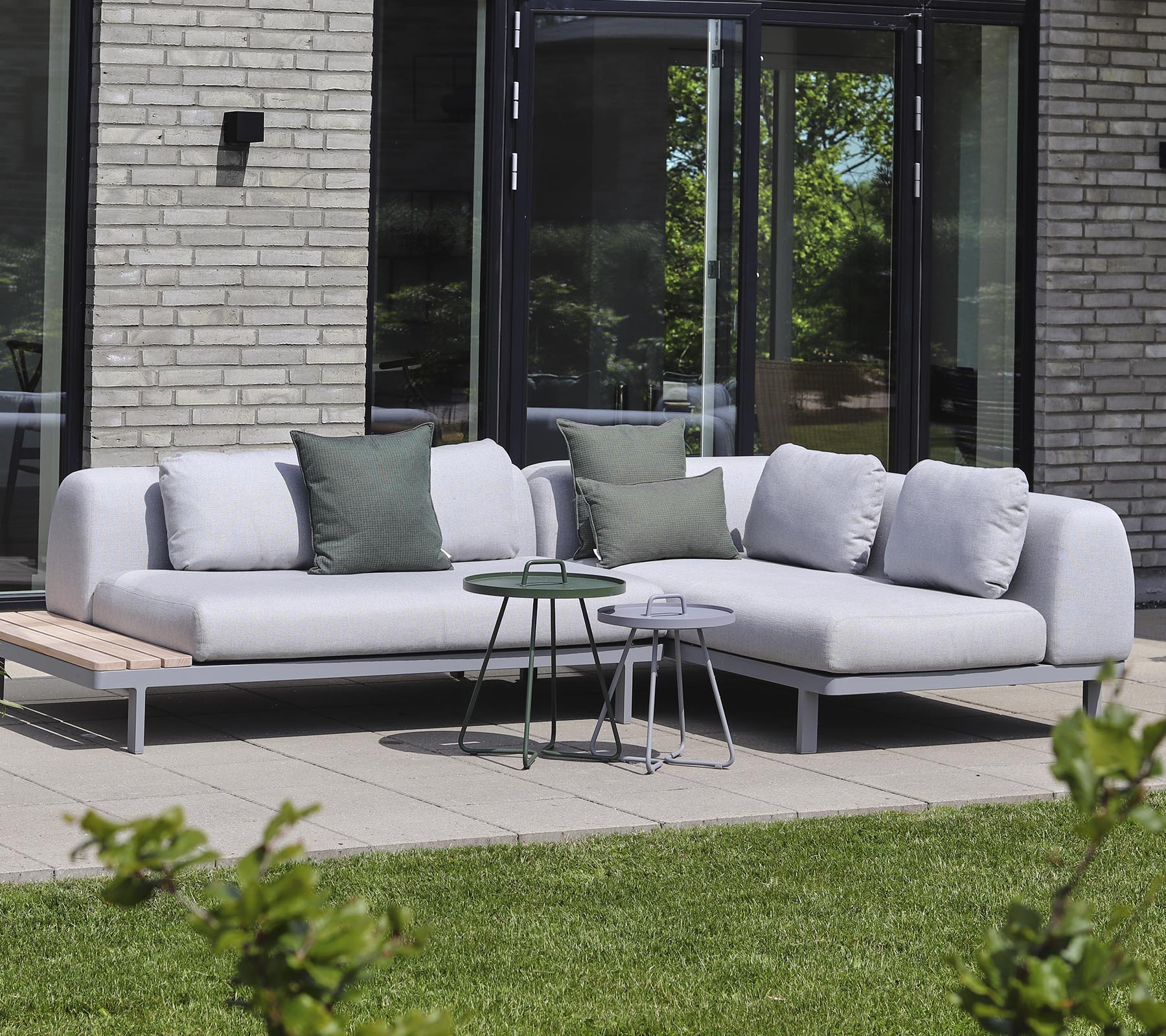 Modern sectional sofa in light fabric with decorative pillows, paired with small side tables in a tranquil setting.