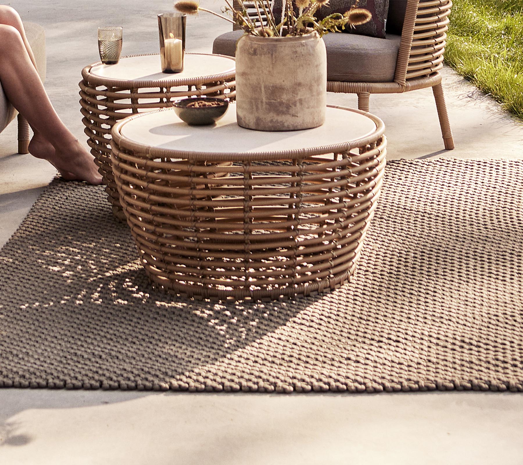 A cozy seating area featuring woven tables, a decorative vase, and a textured rug, perfect for enhancing a stylish space.