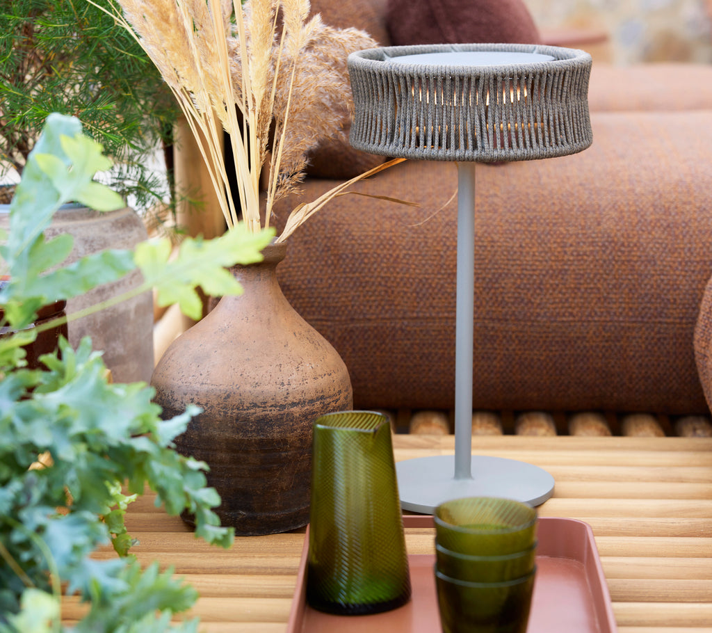 A medium illusion lamp atop a club tray, surrounded by green glasses and decorative plants.