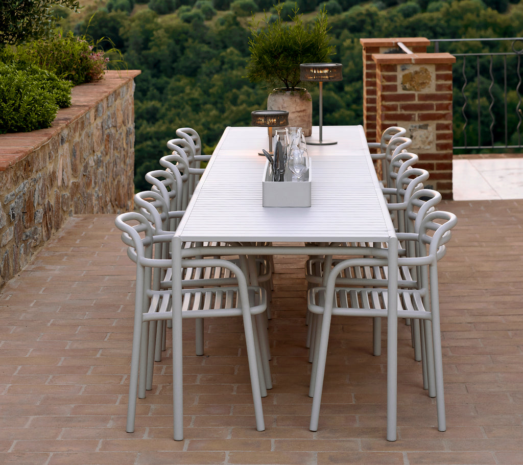 A long, white table surrounded by several sleek, light chairs, with decorative items and greenery enhancing the stylish setting.