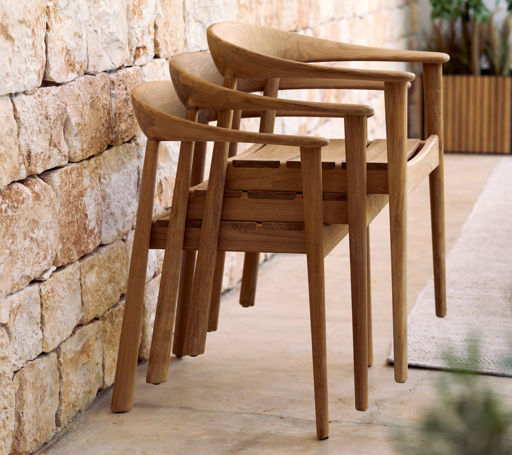 Stacked wooden chairs against a stone wall in a modern lounge setting.