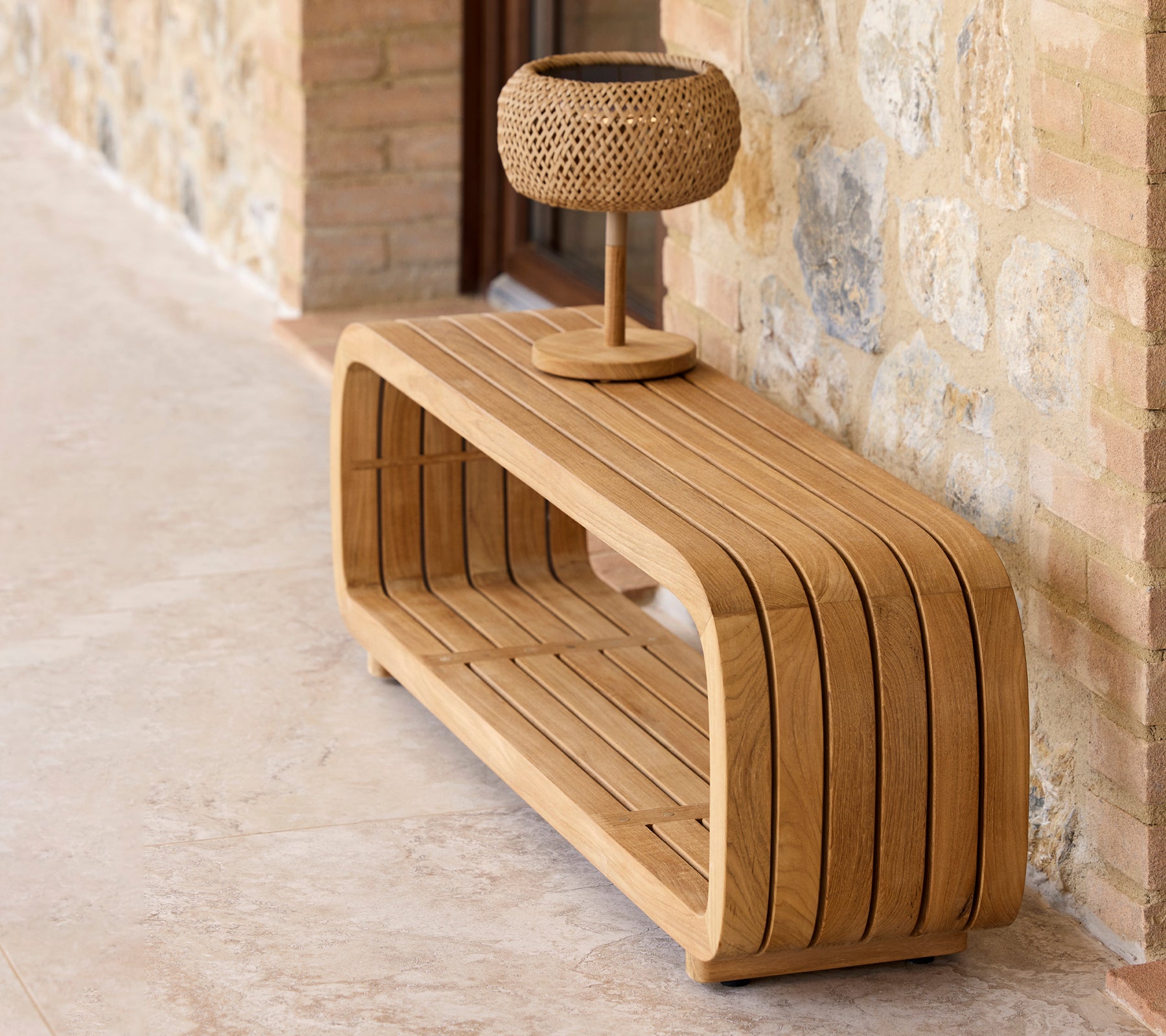 A sleek, wooden coffee table with a curved design, featuring a small decorative lamp on top.