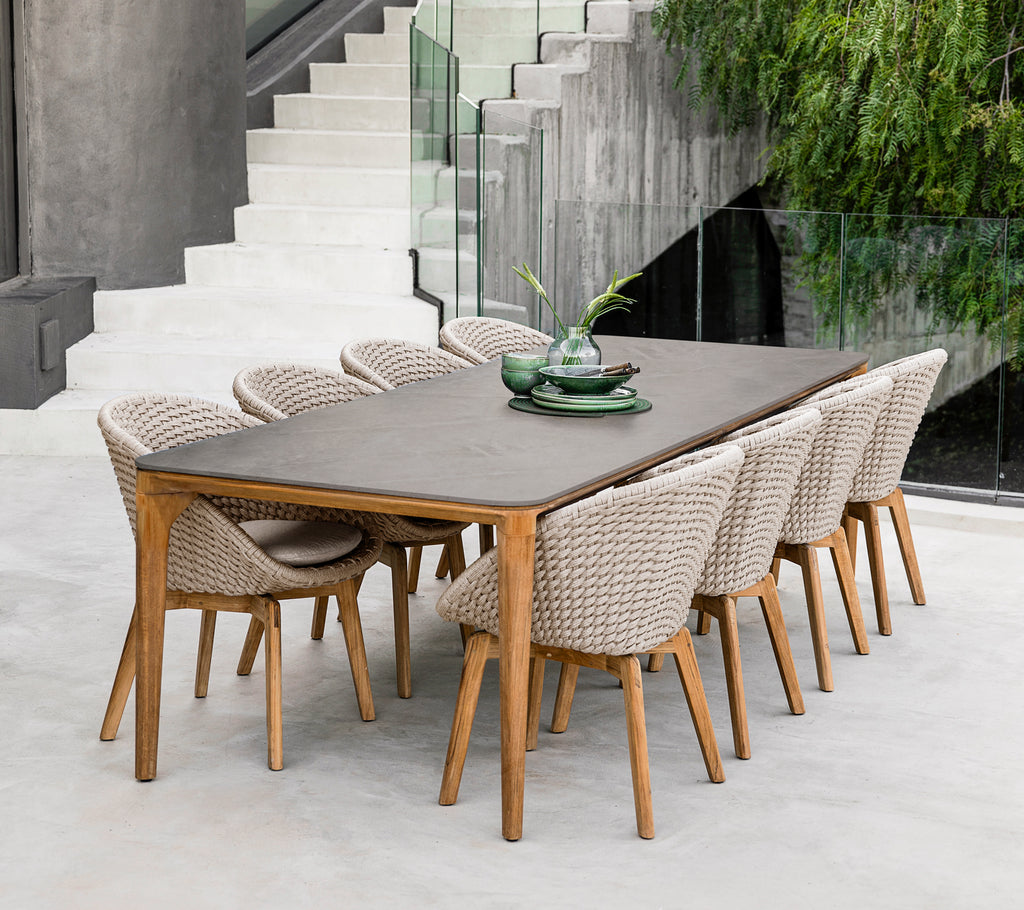 Modern brown dining table with woven chairs in a contemporary setting.