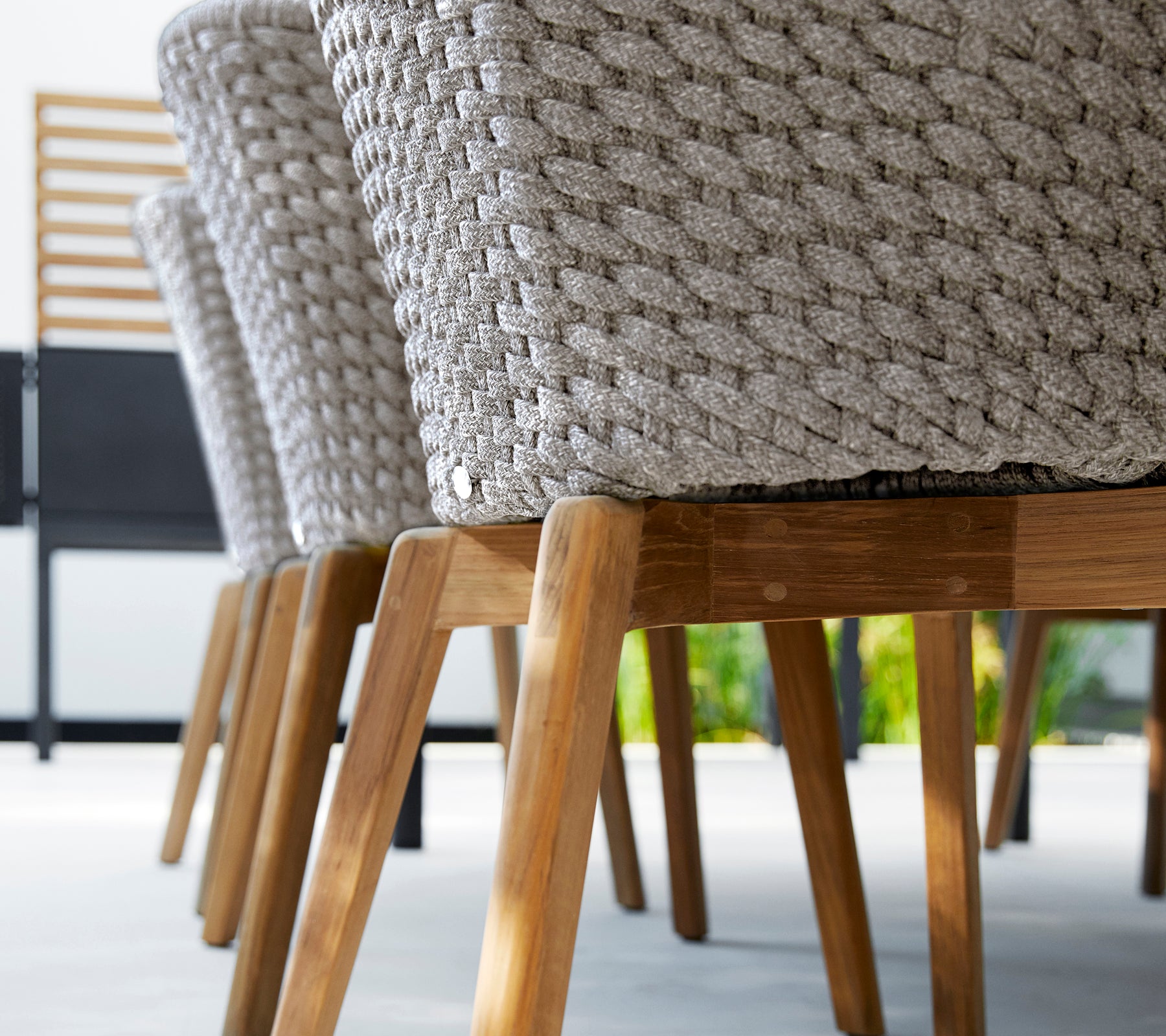 Modern grey chair with a woven design and wooden legs.