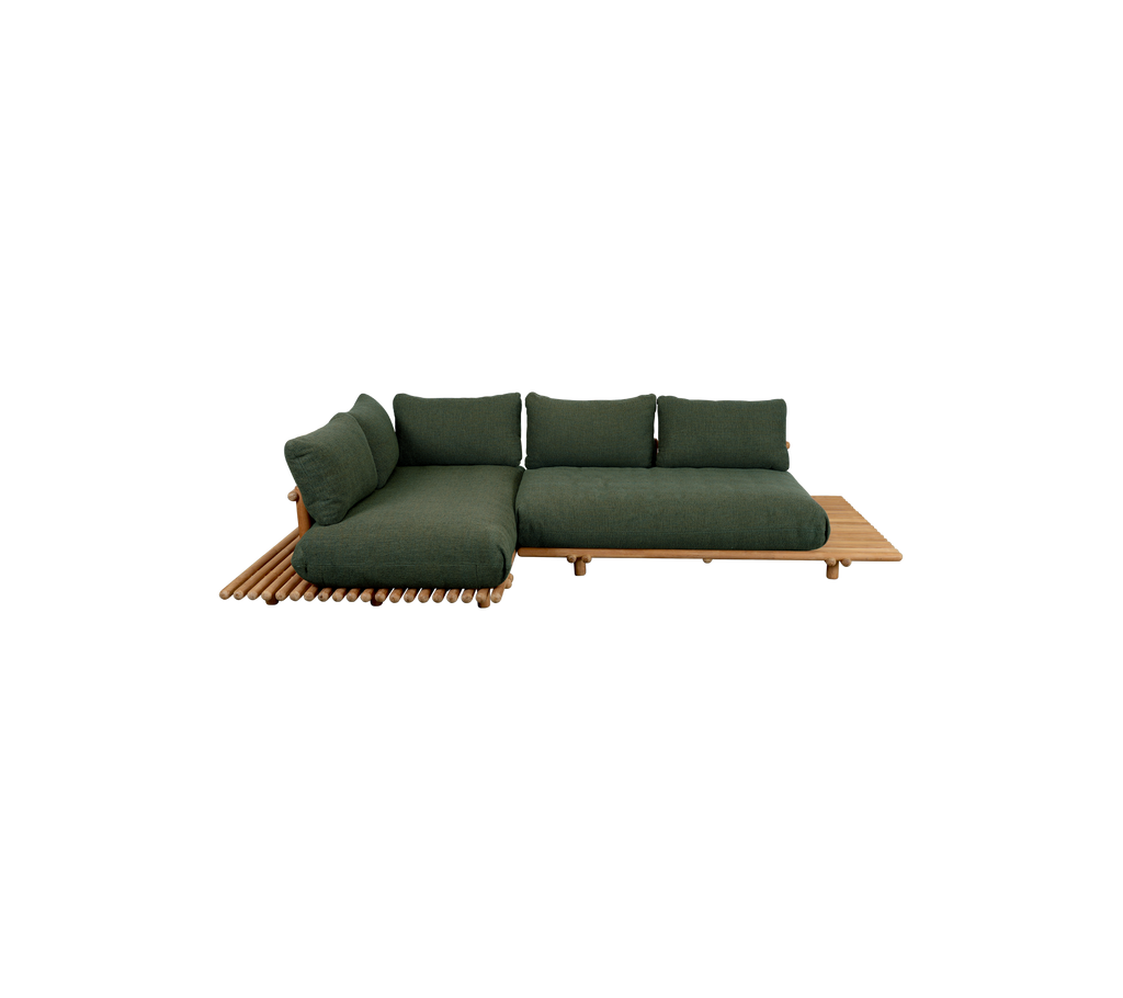 Modern green sofa with a teak platform in a relaxed lounge setting.