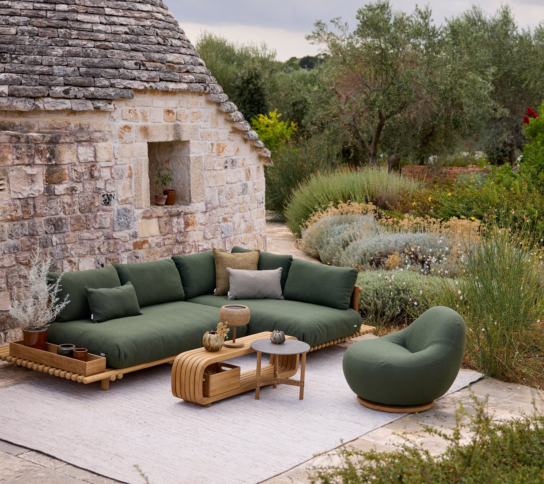 Modern green sofa with round chair and coffee table in an outdoor lounge setting.