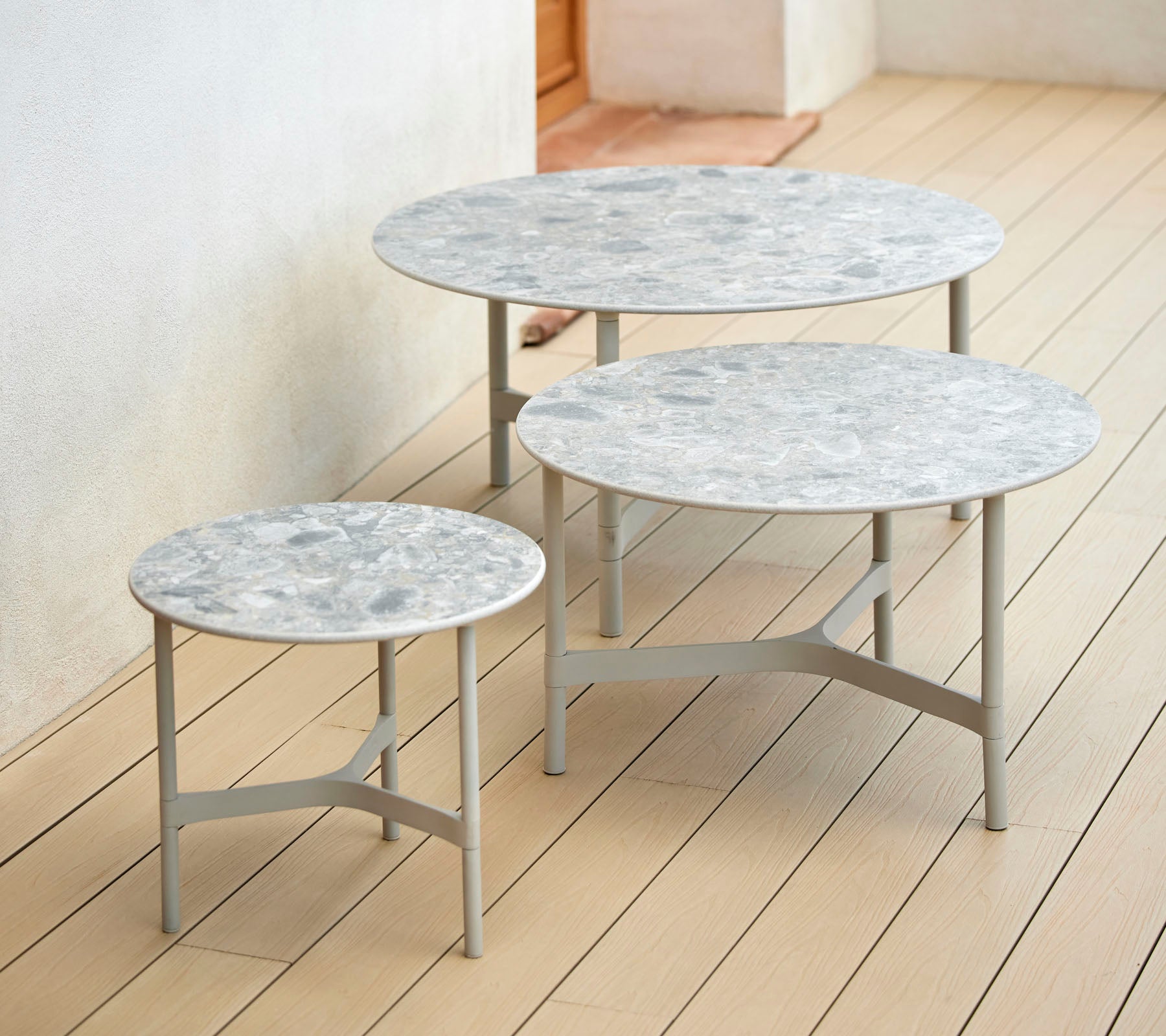 Three circular tables of varying heights with marble tops and slender metal bases, arranged together for a stylish display.