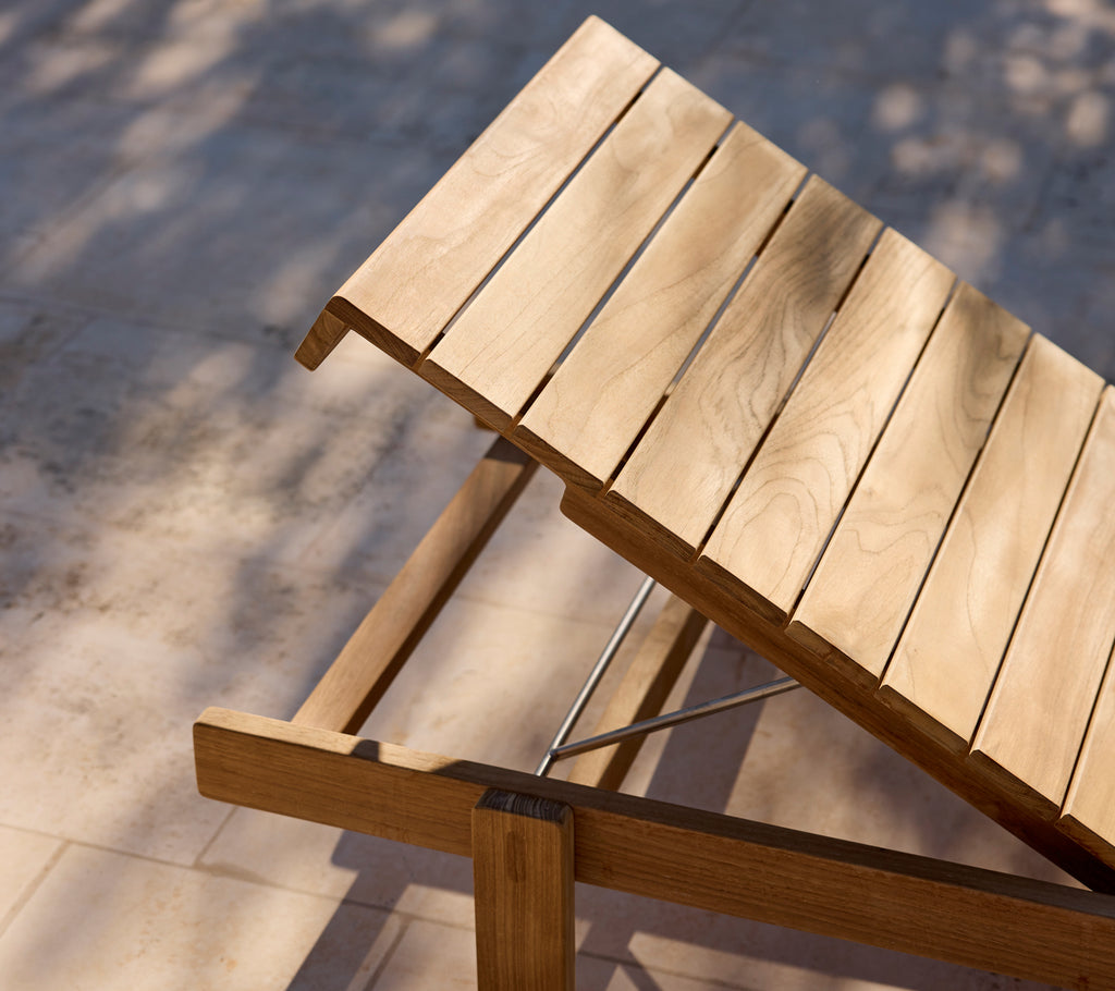 Modern wooden lounge chair with adjustable backrest on a sunlit patio.