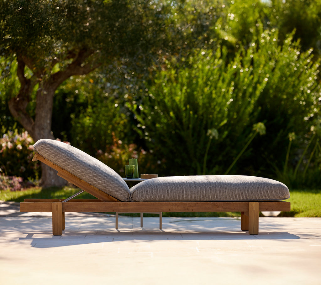 Modern grey lounge chair in an outdoor garden setting.