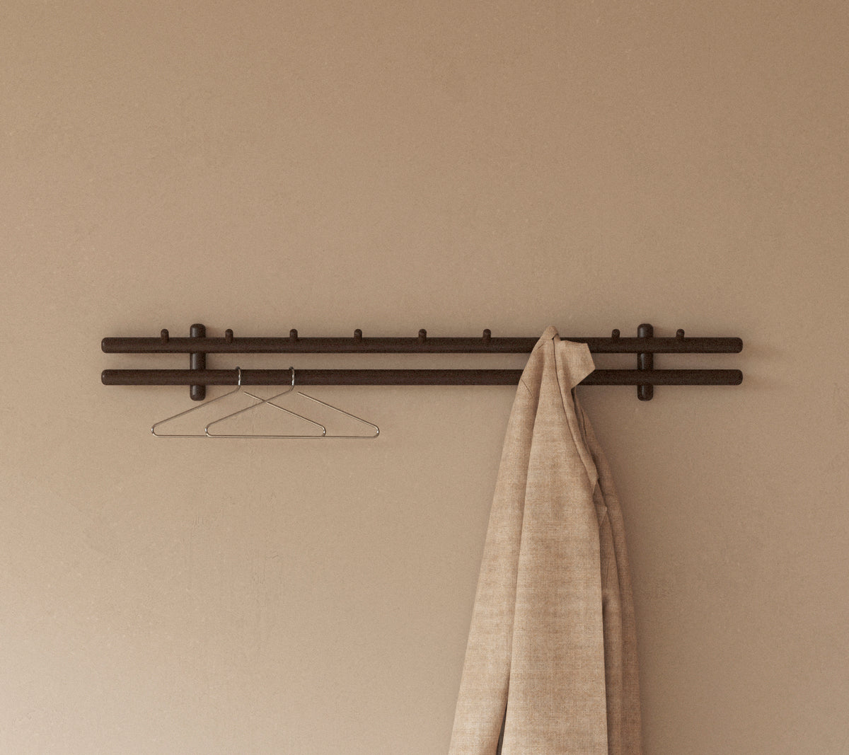 A coat rack featuring wooden sticks and a hanger, with a large, textured rag hanging from it against a smooth wall.